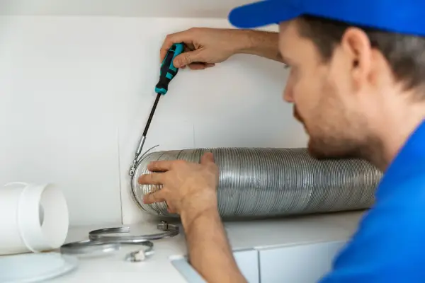 Ventilation Systems in Saudi Arabia - Worker installing a flexible aluminum ventilation tube for an air exhaust system