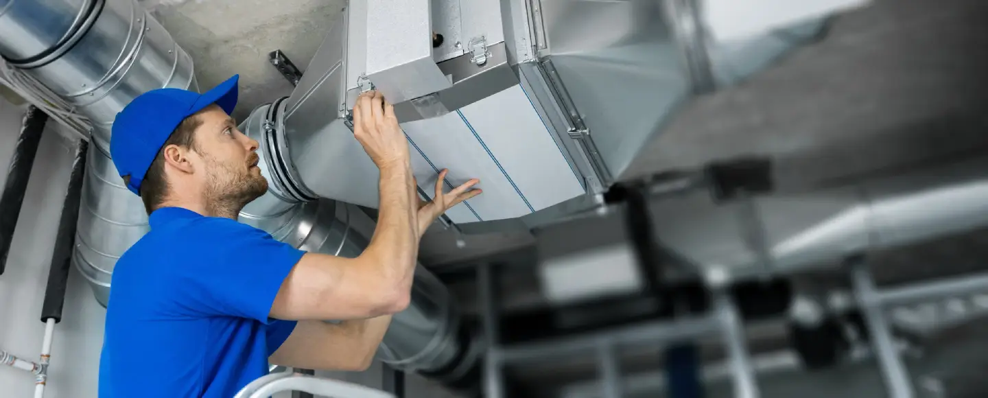Ventilation system installation and repair service with HVAC technician at work